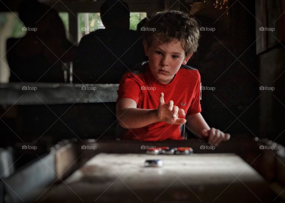 Playing Shuffleboard. Boy Playing Indoor Shuffleboard
