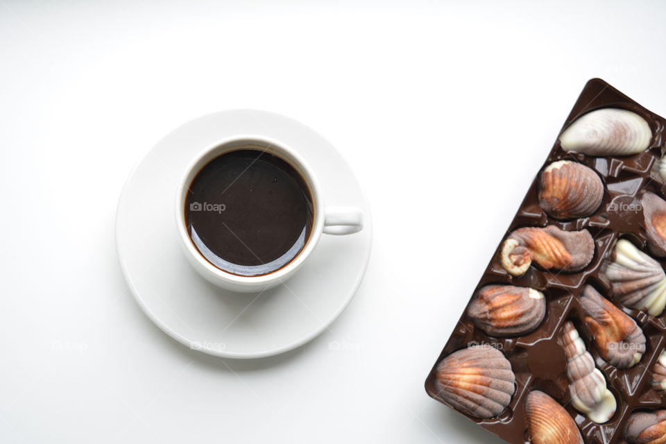 cup of coffee with chocolate candy top view on a white background