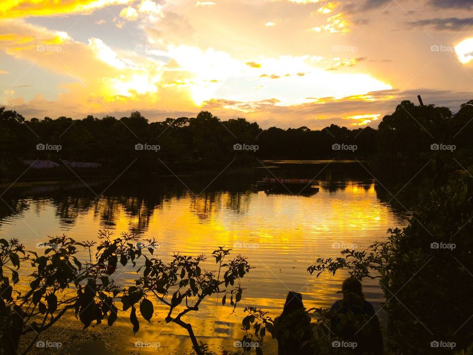 Dramatic sky and silhouette of trees reflected on lake