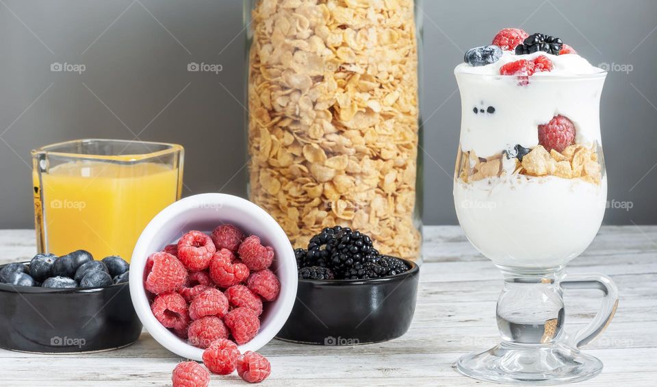 Breakfast with cereal, berries, yoghurt and orange juice