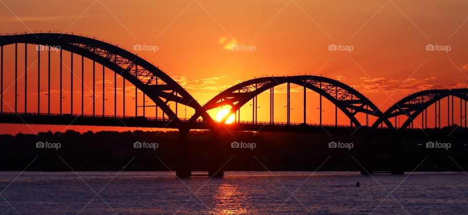 Wide view of sunset behind a bridge on the Mississippi River between Rock Island, Illinois, and Davenport, Iowa. 