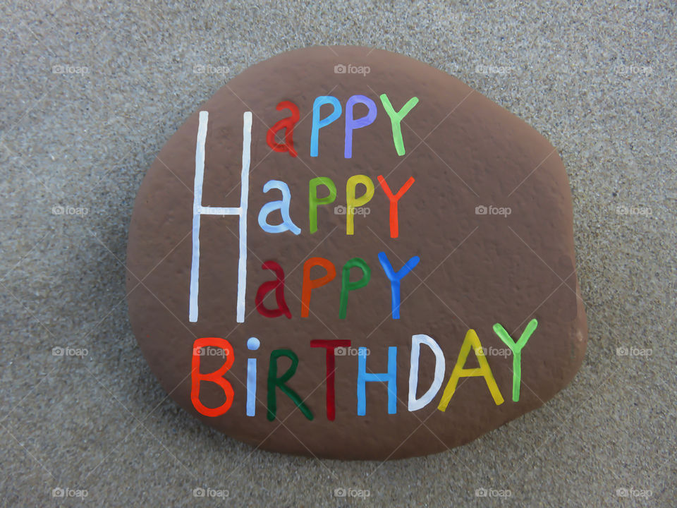 Happy,Happy,Happy Birthday on carved and colored letters on a stone