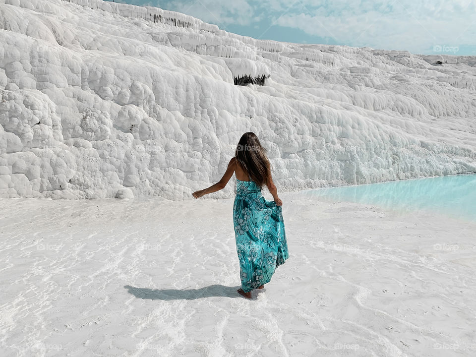 Young woman in blue dress walking by the white chalk landscape 