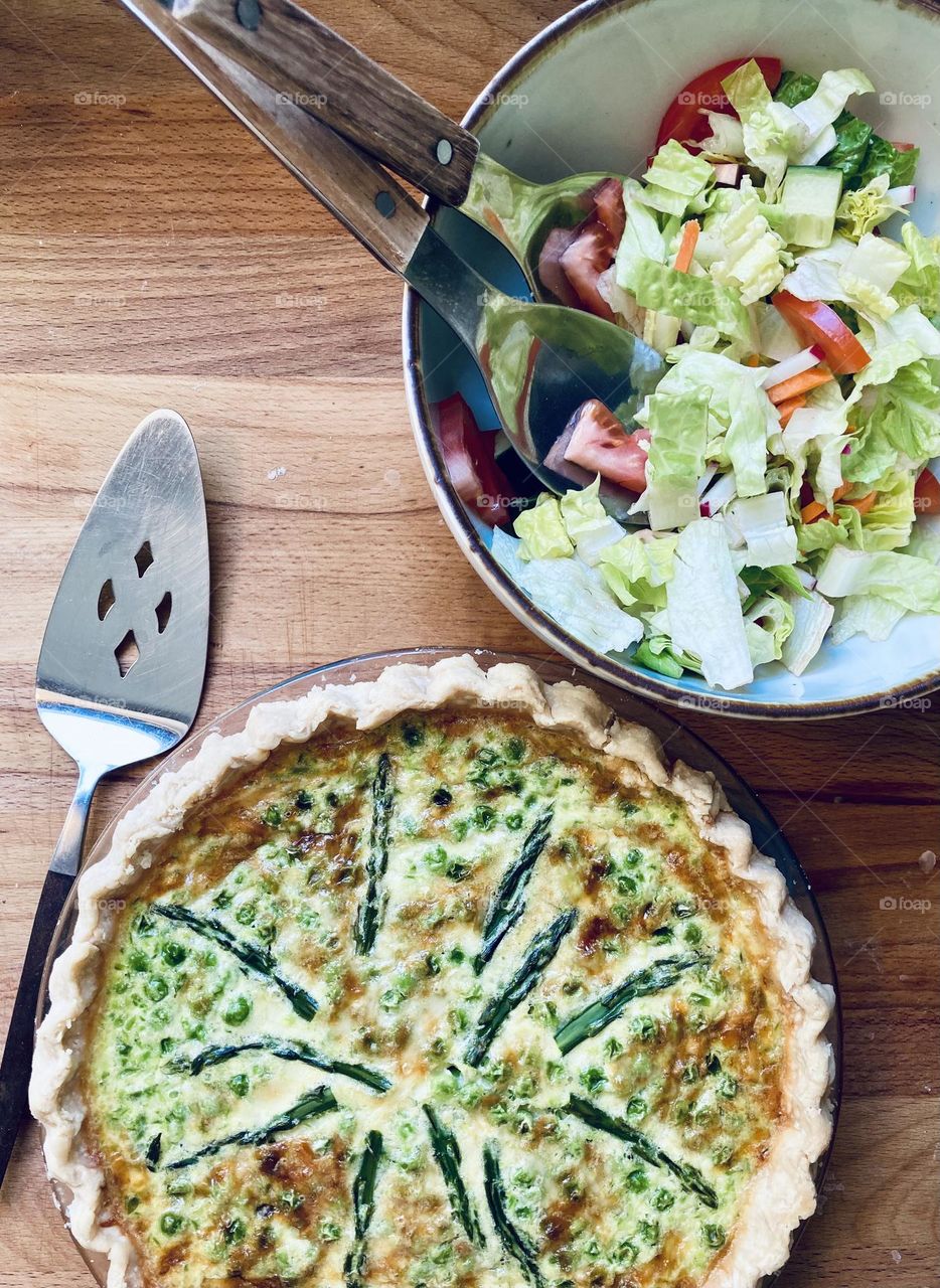 A quiche filled with spring vegetables like asparagus and peas is a delicious and nutritious brunch served with a green salad