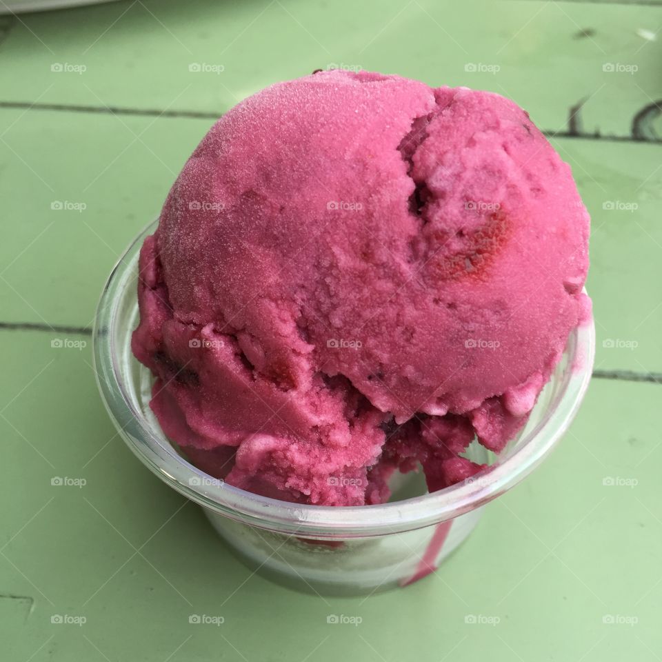 A scoop of rasberry sorbet in a colorful setting great for any use.