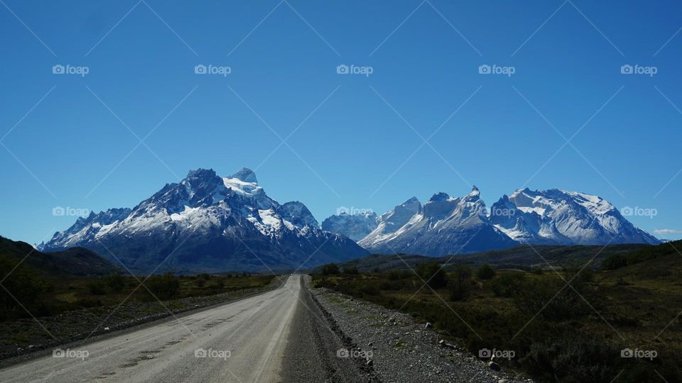 Desolate road leading to snowy mountains