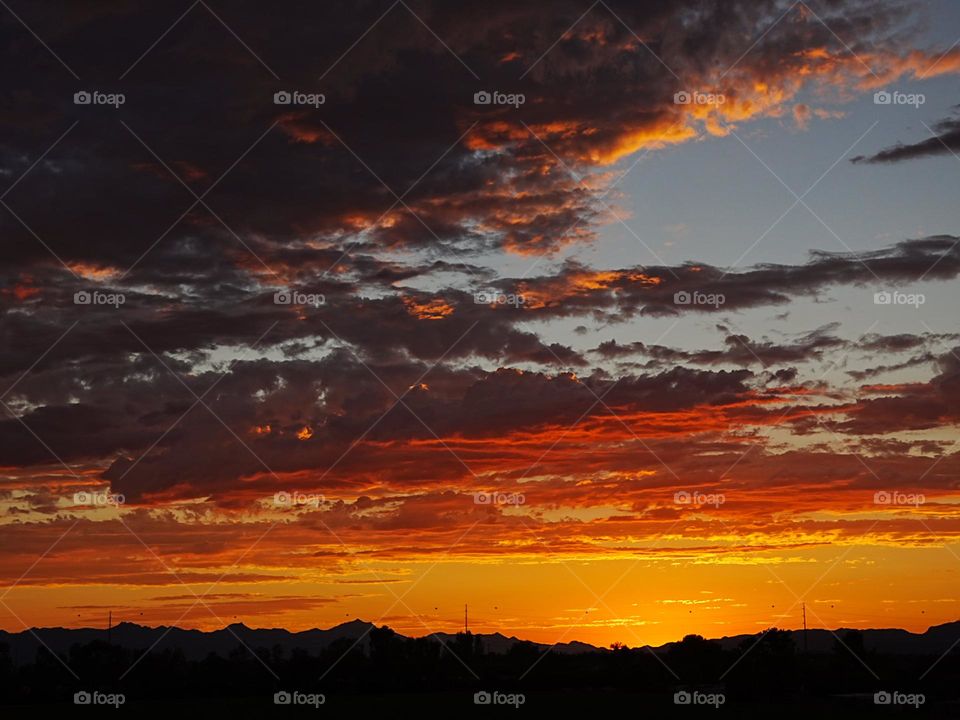 A beautiful desert sunset as the sun casts an orange glow after setting behind the Estrella mountains
