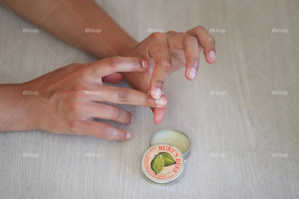 Beautiful woman's hands using Burt's Bees cuticle cream