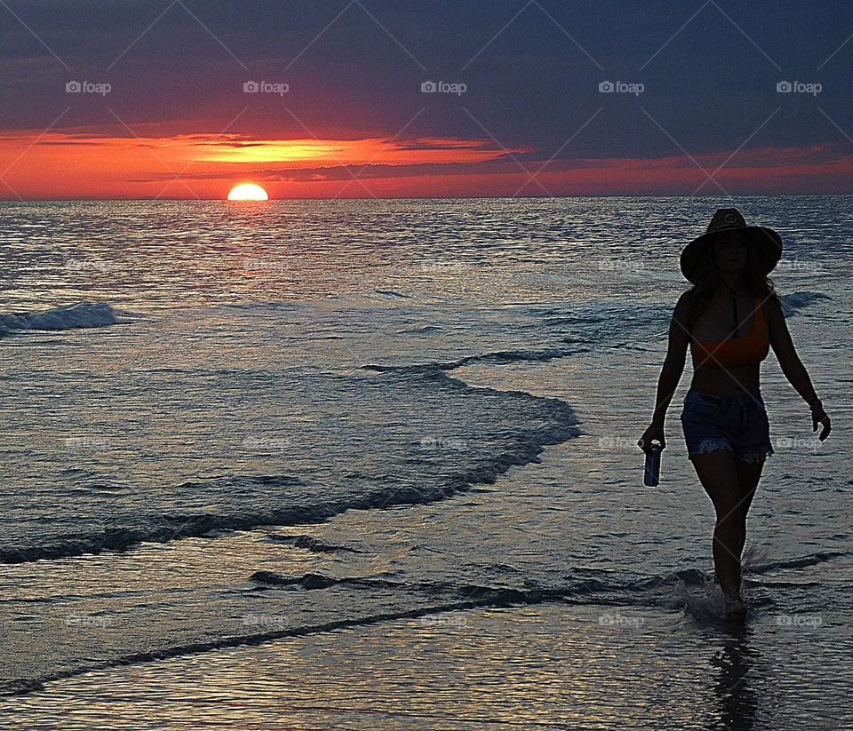 A women walks along the Gulf of Mexico during the last light of the night - THE DESCENDING SUNSET 