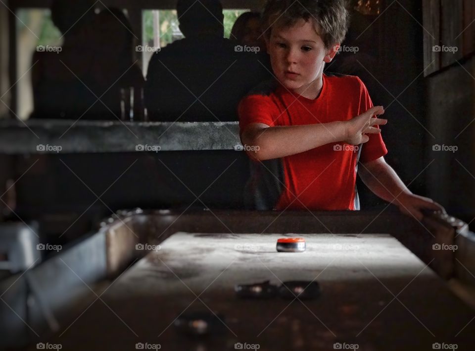 Shuffleboard. Young Boy Playing Indoor Shuffleboard
