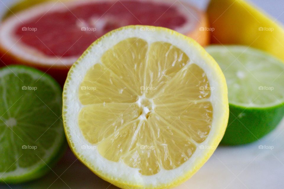 Still life of of grapefruit and lime halves, closeup of lemon on white background