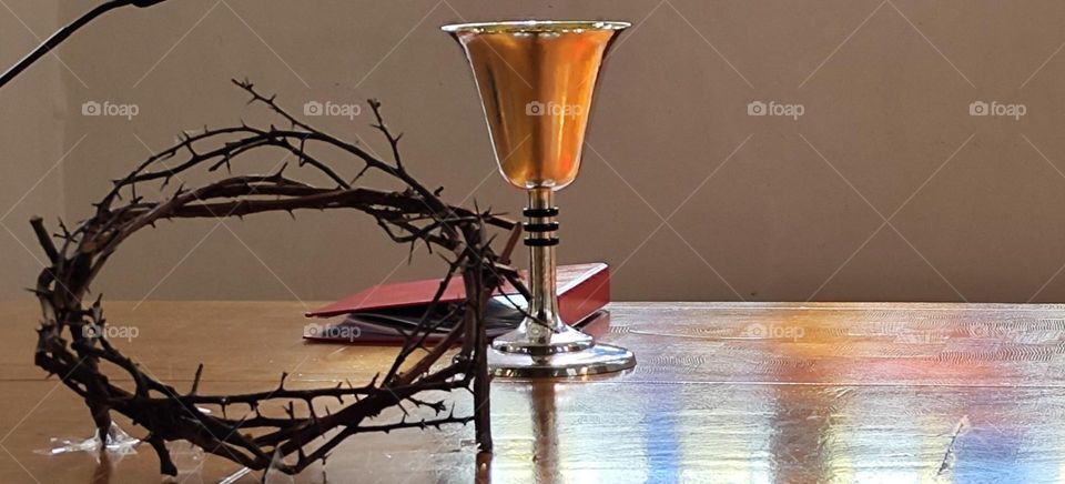 The crown of thorns next to the gold chalice that holds the wine that the faithful drink in remembrance of “Jesus Christ” our Savior is a symbol for death, resurrection and eternal life seen in “Garmisch Partenkirchen”. 2023. Hypnotic Productions