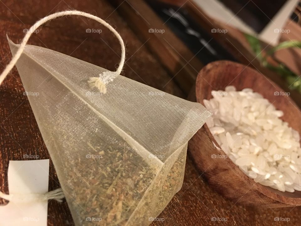 Closeup of Japanese style dried green tea in tea bag with rice in bowl symbolic of healthy eating and lifestyle choices 