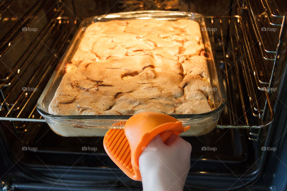 Girl takes an apple pie from the oven