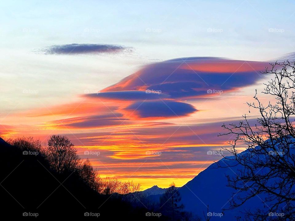 Nature. Sunset. Above the mountains, clouds in the shape of a fiery angel's wing