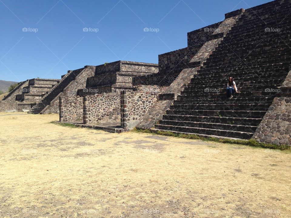 Woman sitting on ancient pyramid 