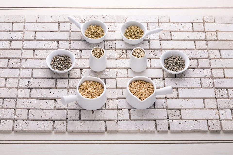 minimalist symmetrical composition of mini containers with different seeds, rustic base of small stones