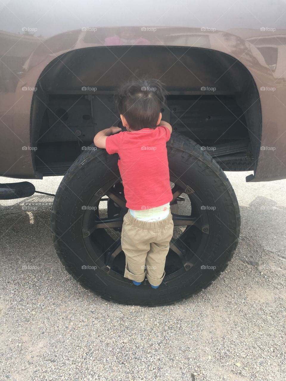 2 year old boy standing on truck tire