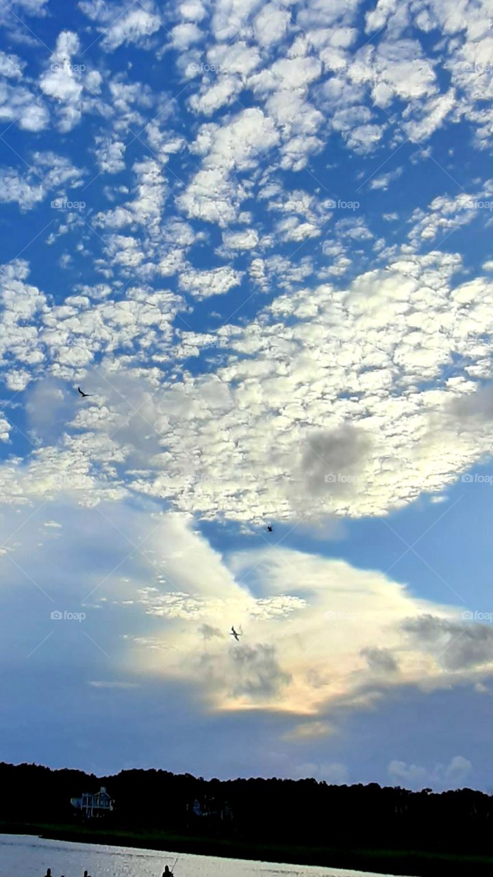 cloud cover over sunset at the salt marsh birds and fishermen in silhouette