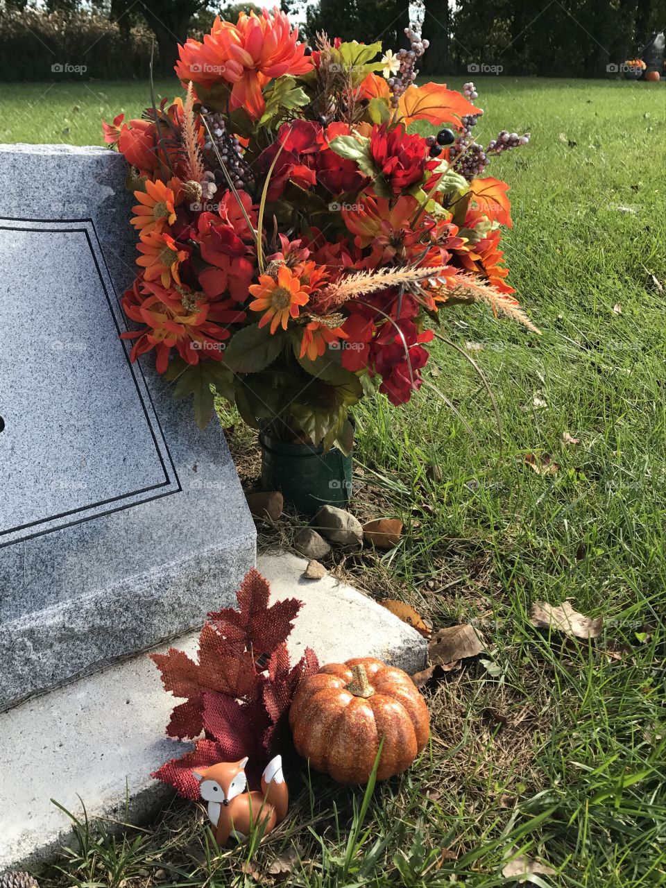 Someone placed a cute fox figurine and a bouquet of flowers next to a headstone.