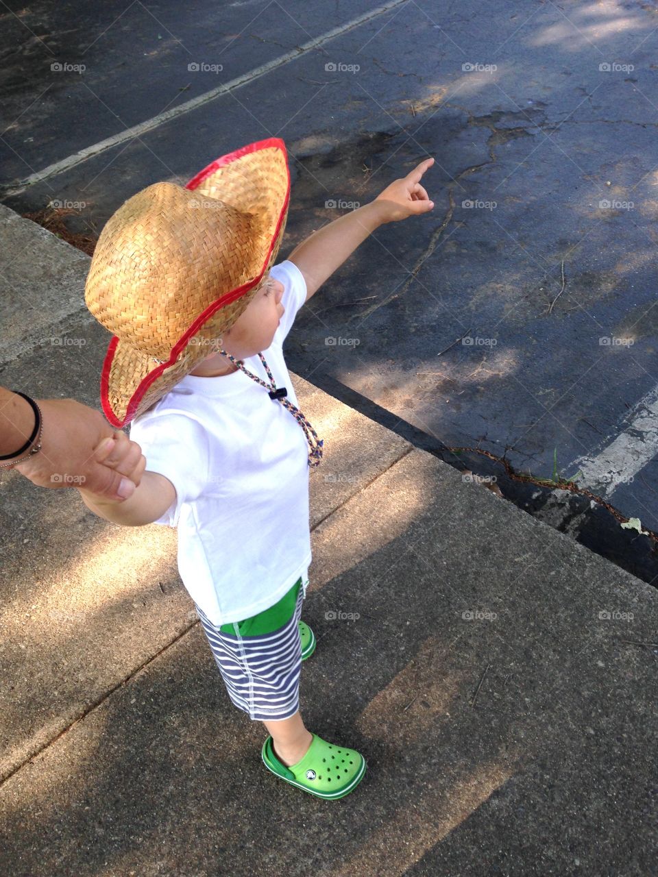 Child holding his mother's hand and pointing.