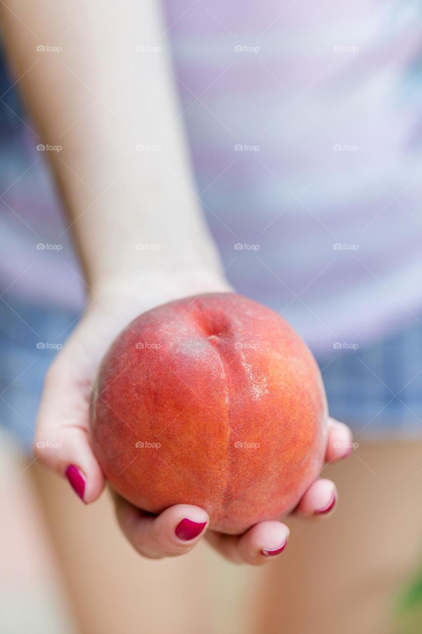 Juicy ripe peach on female hands, closeup