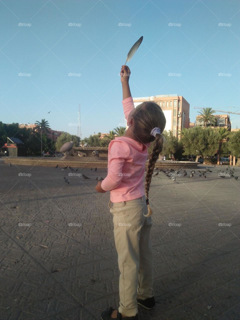 a young girl holding a feather.