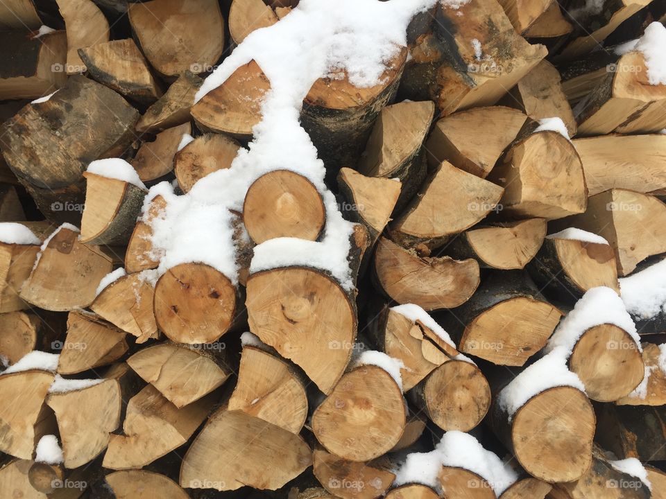 Pile of cut firewoods covered in snow