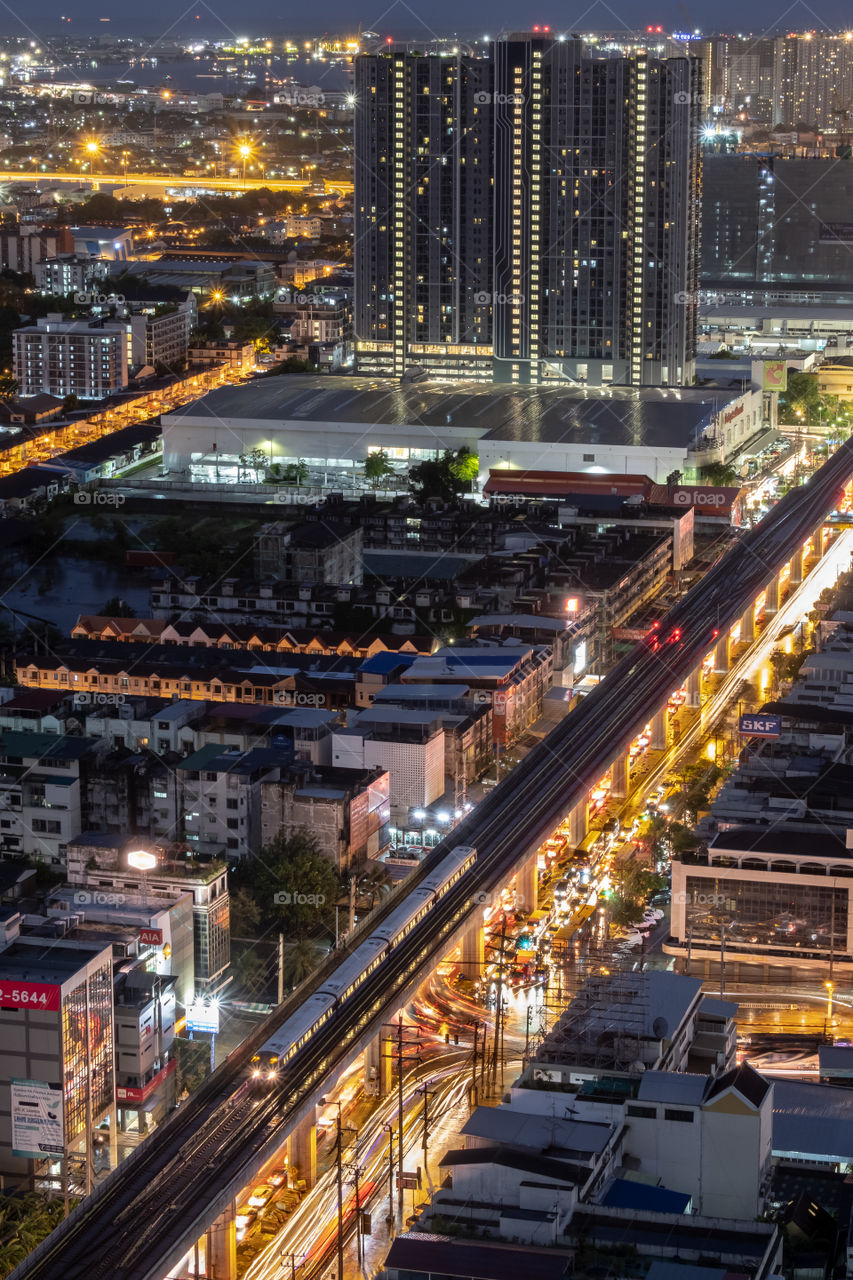 BTS train above beautiful line of vehicle light and reflect on waterlogging after heavy rains in Bangkok Thailand