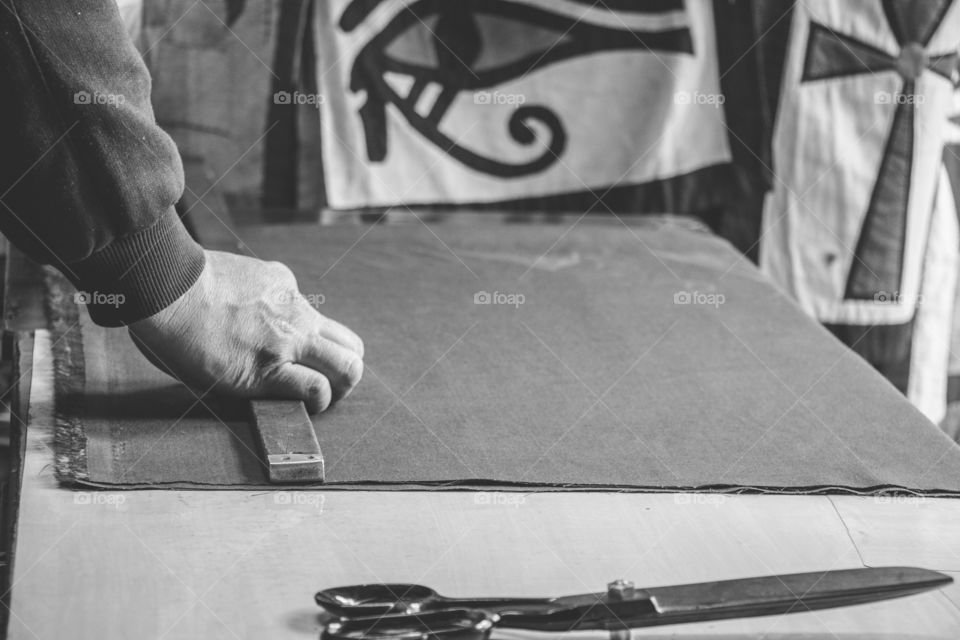 Side view of a tailor cutting cloth