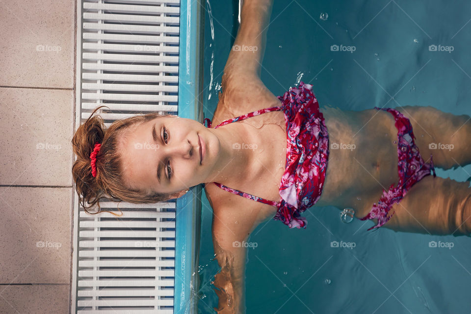 Young woman swimming and relaxing in swimming pool. Candid people, real moments, authentic situations