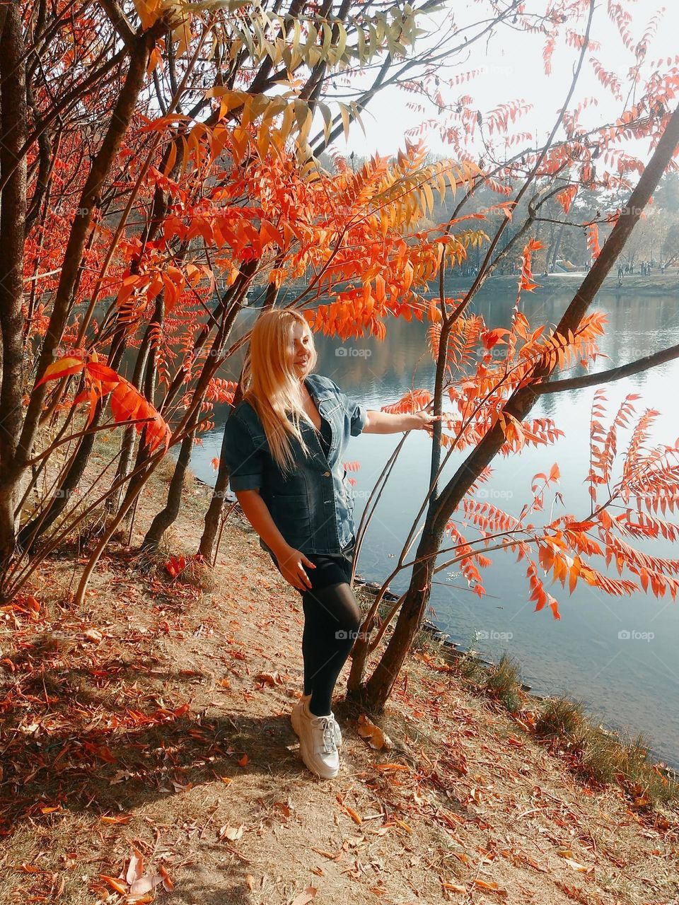 a girl stands near a beautiful autumn tree