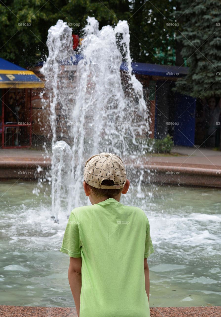 child and water fountain city summer time