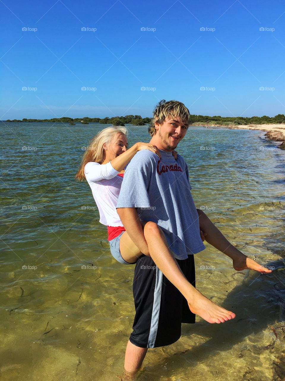 Young couple playing in water at ocean in Australia piggyback 