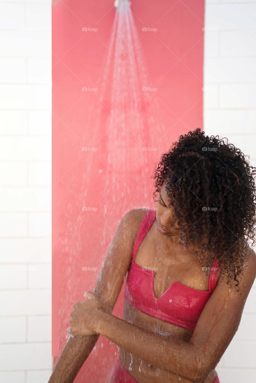 Black woman with Afro hair using outdoor shower