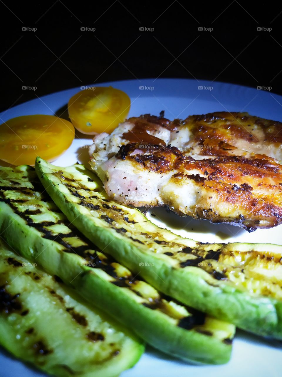 Dinner.  Plate with grilled zucchini, grilled meat steak and yellow tomato