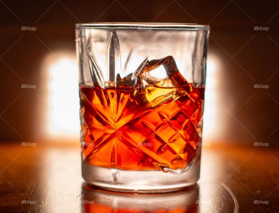 A detailed glass with a liquor inside on ice in a dark moody scene 