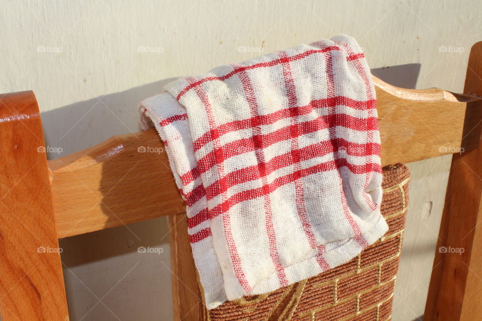 white towel with red lines on a wooden chair