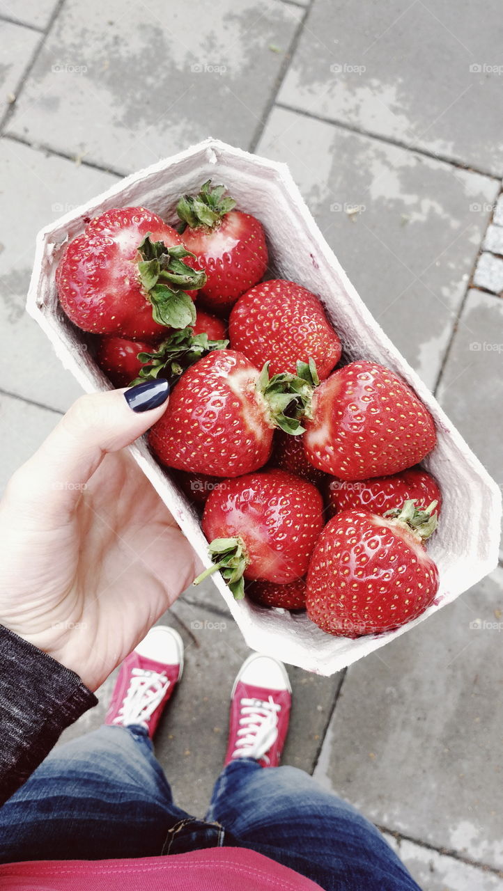 Hand holding box of strawberries