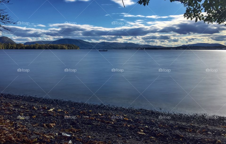 Sailing on The Hudson . A long exposure shot of the Hudson River, with a sailboat anchored and the Appalachian mountains in the background. 