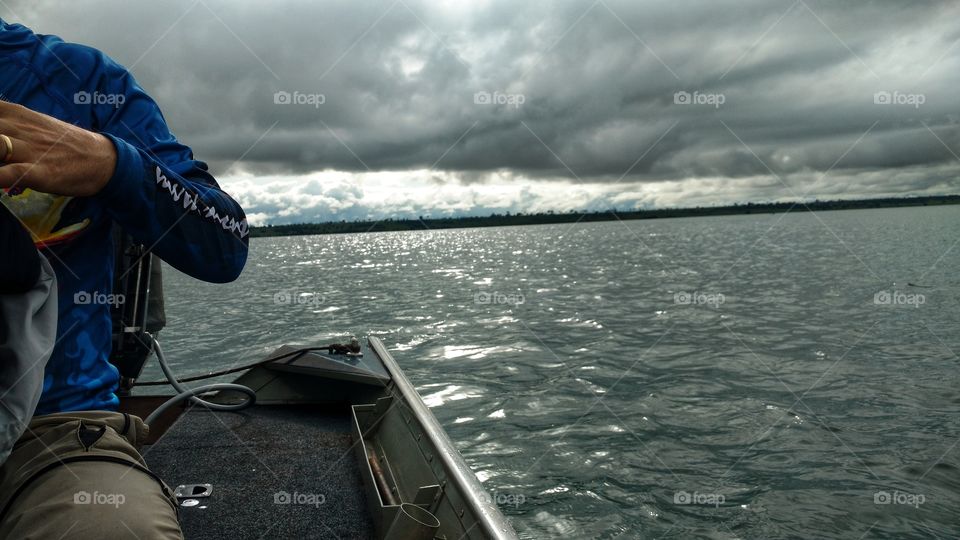 Água, rio. Pescaria em barco. Céu escuro nublado.