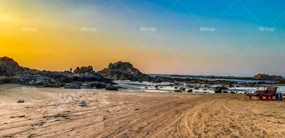 Beauty of Beach - The beach is surrounded by colourful Nature that is sky and small rock hills.