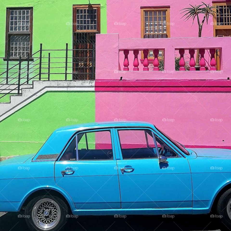 a car front of colored houses