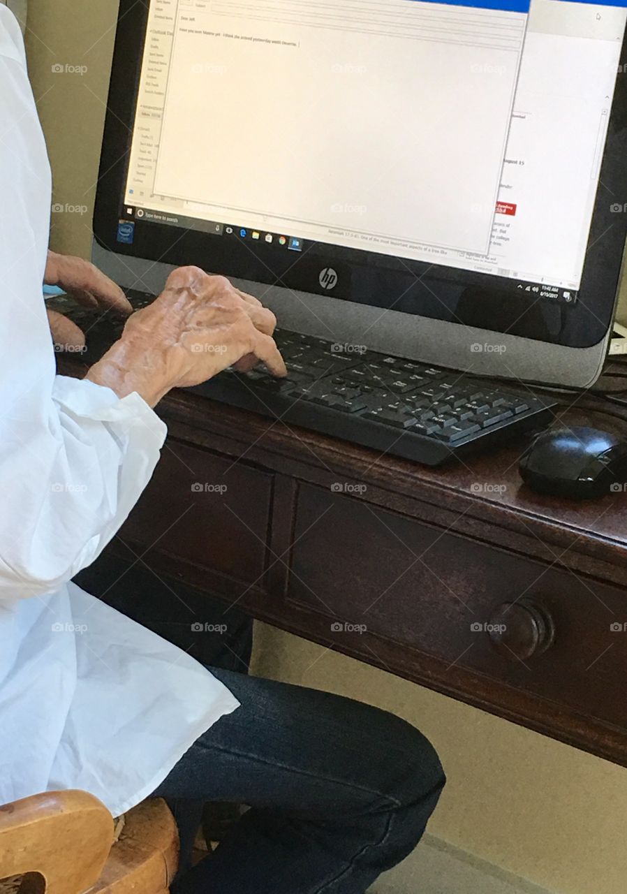 Arthritis hands of elderly woman at computer keyboard 