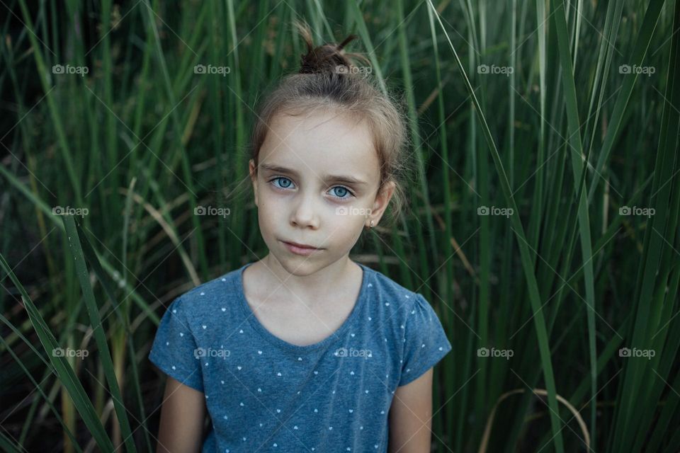 Summer Portrait of a Girl with Green Grass and Blue Skies in the Background