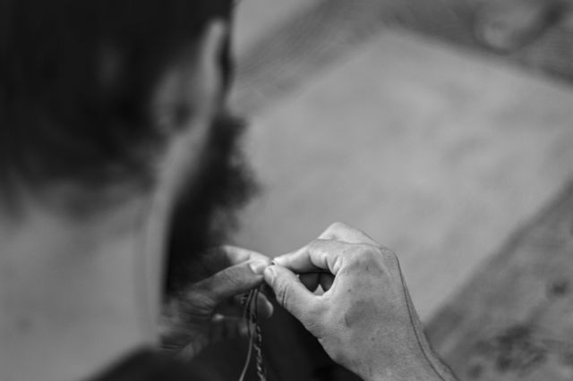 A foto mostra um jovem realizando trabalho artesanal em sua oficina.