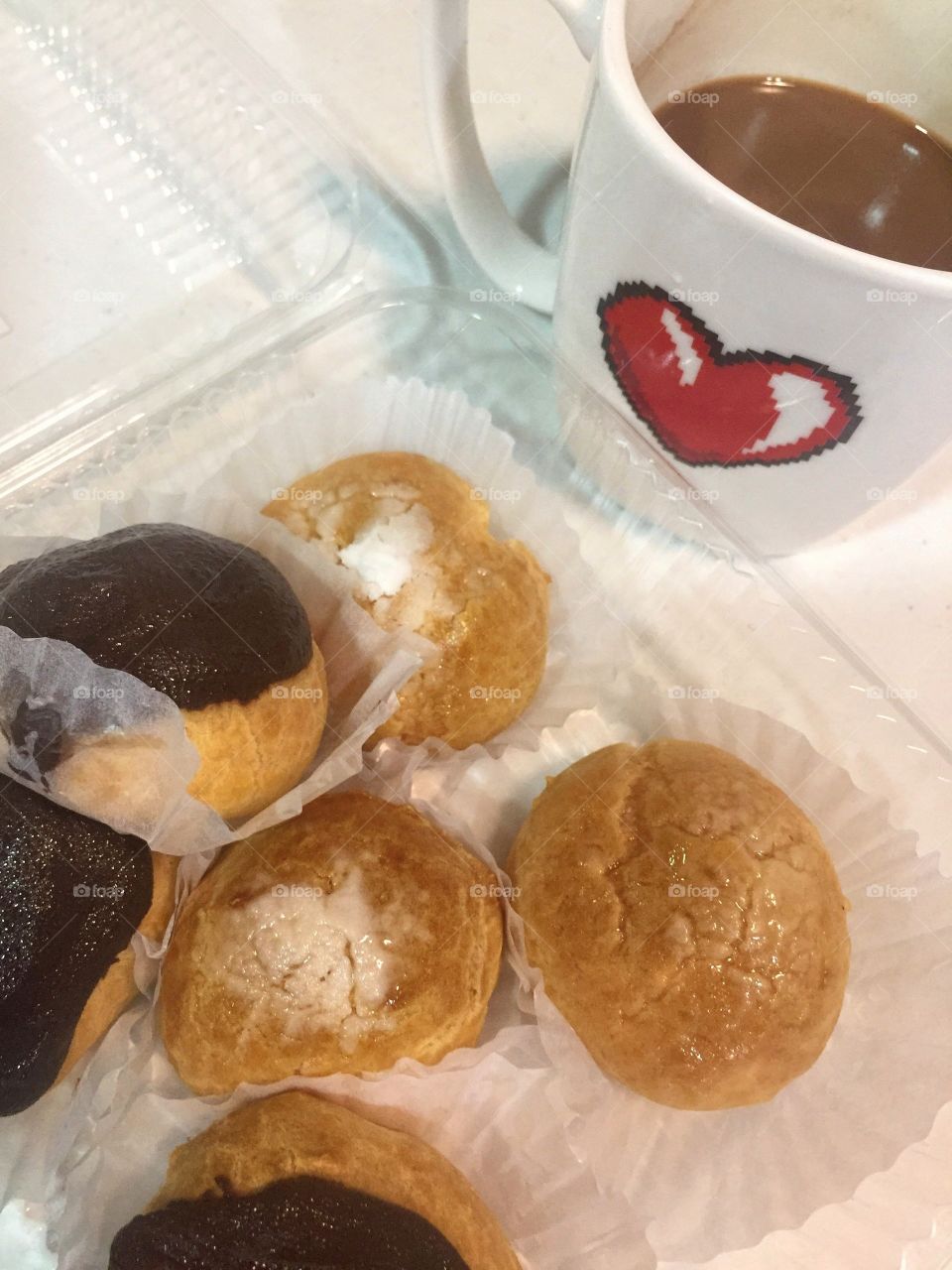Chocolate glazed and sugar-dusted mini cream puffs paired with coffee.