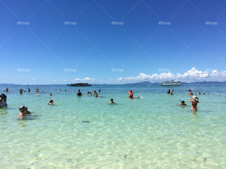 Tourists enjoying pristine water on white sand 
