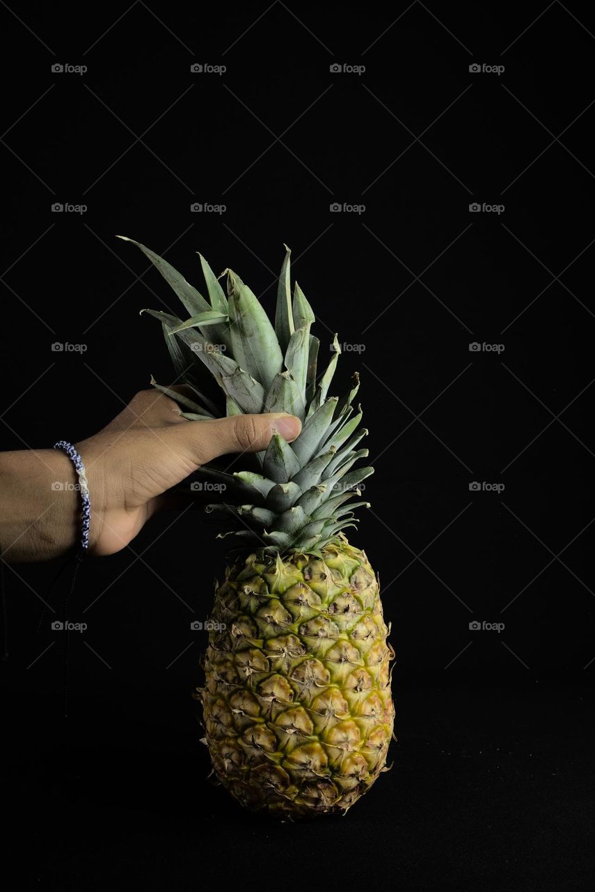 Holding a pineapple on a black background