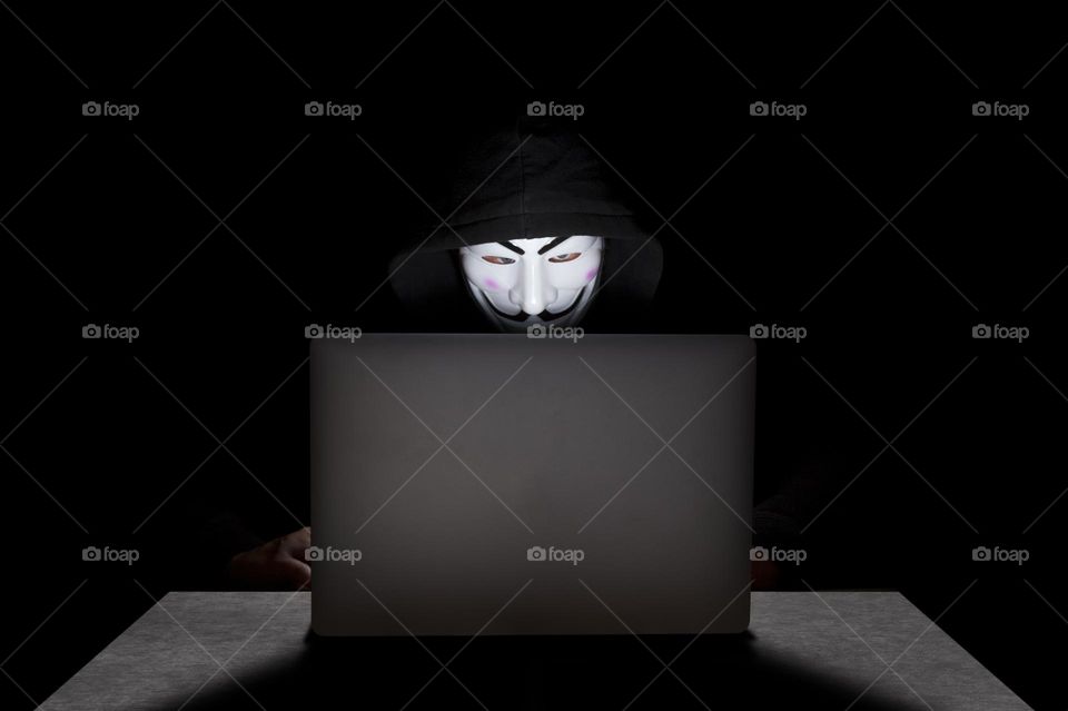 Member of the Anonymous doing cybercrime on his laptop